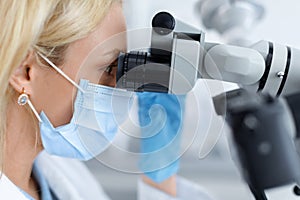 Female dentist using modern equipment for treating in dental clinic