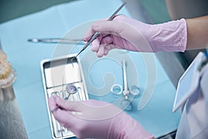 Female dentist using sterile dental instruments in office