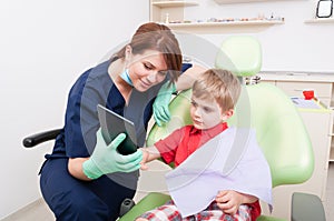 Female dentist using tablet to relax kid patient