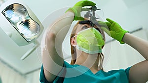 Female dentist wearing magnifying glasses with light, professional equipment