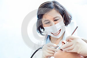 Female dentist wearing smiling face mask during a dental procedure