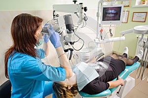Female dentist working with microscope at modern dentist clinic