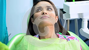 Female in dentistry chair looking at doctor before procedure on plaque removal