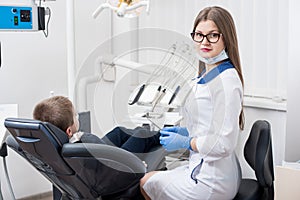 Female dentists examining and working with boy patient. Kid boy in dentist`s chair