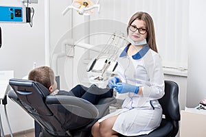 Female dentists examining and working with boy patient. Kid boy in dentist`s chair