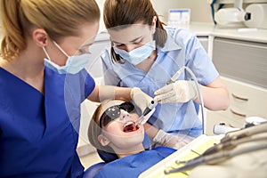 Female dentists treating patient girl teeth