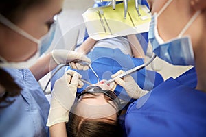 Female dentists treating patient girl teeth