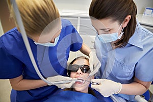 Female dentists treating patient girl teeth
