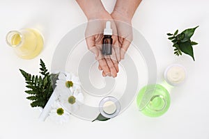 Female dermatologist with bottle of skin care product and ingredients on white background