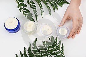 Female dermatologist with jars of skin care products on white background