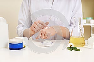 Female dermatologist testing skin care product at table
