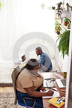 Female designer draw on paper while man use laptop