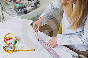 Female designer drawing paper patterns. Exclusive clothes making concept. Workplace of seamstress photo