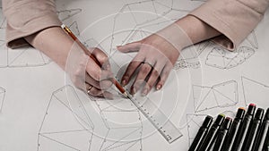 Female designer makes a working drawing. Workplace of a toy designer. Markers, ruler, pen and pencil are on the drawing