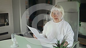 Female designer working at home office on new ideas. Caucasian woman sitting at her desk with laptop reviewing few