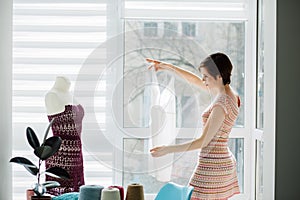 Female designer working with knitted dress in the cozy studio interior, freelance, lifestyle, inspiration concept