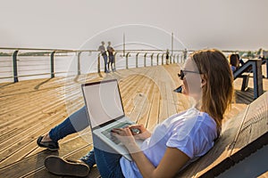 Female developer sites working on netbook, sitting on bench