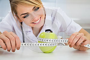 Female dietician measuring green apple photo