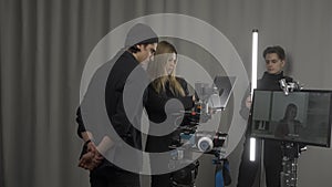 Female director, camera operator and lighting technician in the studio during filming. The lighting technician adjusts