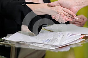 The female director working in the office sits at the table and shakes hands with her partner