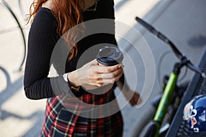 Female dirt bike rider drinking coffee in skate park. Young athlete girl chilling with coffee after a ride