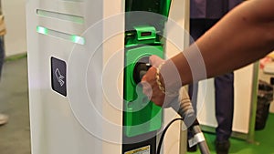 Female disconnecting electric vehicle plug from socket at charging station