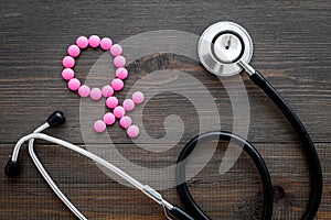 Female diseases concept. Stethoscope near female sign on dark wooden background top view