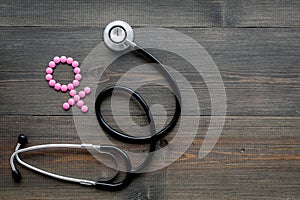 Female diseases concept. Stethoscope near female sign on dark wooden background top view copy space