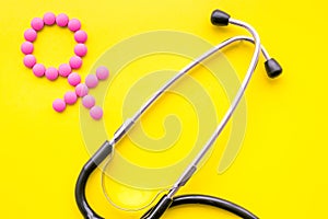 Female diseases concept. Stethoscope near female sign on yellow background top view