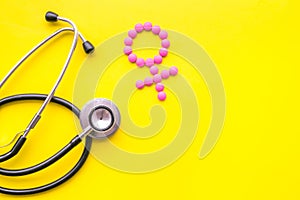 Female diseases concept. Stethoscope near female sign on yellow background top view copy space