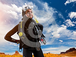 Female diver in diving gear poses on the beach