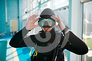 Female diver in scuba suit sitting at the poolside