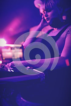 Female dj listening to headphones while playing music