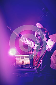 Female dj waving her hand while playing music in bar
