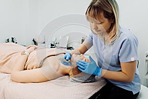 Female doctor applying dermapen device for relaxed woman patient, lying on couch in spa clinic on beauty procedures photo