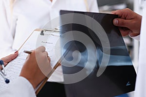 Female doctor arm hold silver pen filling patient complaints