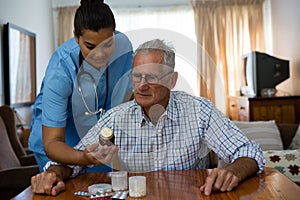 Female doctor assiting senior man in taking medicine