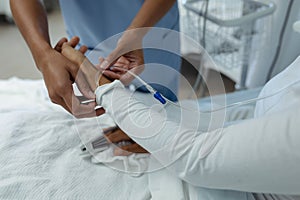 Female doctor attaching iv drip on female patient hand