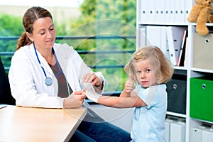 Female doctor bandaging the arm of a little girl