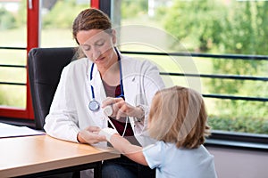 Female doctor bandaging the arm of a little girl