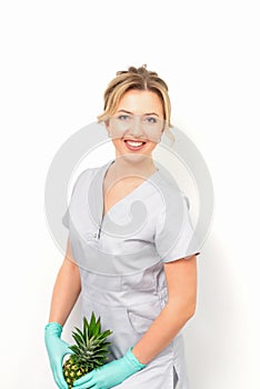 Female doctor beautician with pineapple. Concept of epilation or depilation and intimate hygiene.