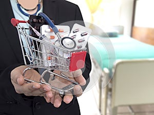 Female Doctor with black suit is holding small shopping cart With colorful pills , injection syringe and stethoscope.