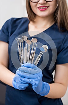 Female doctor with blue gloves holding tools - dental mirrors and dental sondes at the dental office