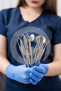 Female doctor with blue gloves holding tools - dental mirrors and dental sondes at the dental office