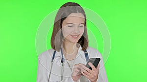 Female Doctor Browsing Smartphone on Green Background