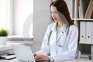 Female doctor brunette sitting at the table near the window in hospital