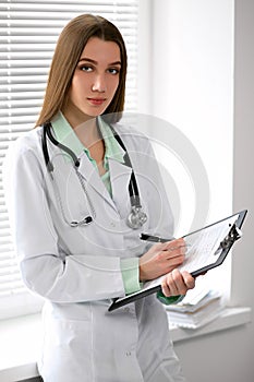 Female doctor brunette sitting at the table near the window in hospital