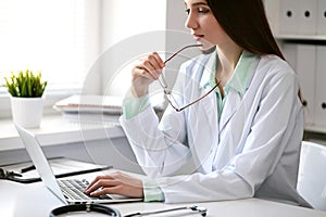 Female doctor brunette sitting at the table near the window in hospital