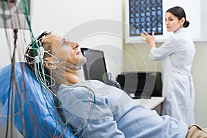 Female doctor carrying out electroencephalography of man photo