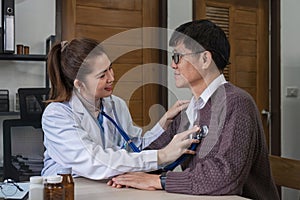 The female doctor in charge holds a stethoscope and listens to the patient. Doctor checking heartbeat examining retired